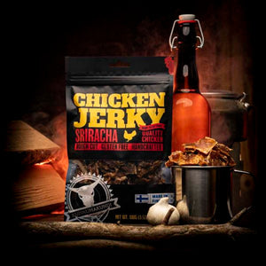 Kuivalihakundi Kylling Jerky Sriracha i et mørkt rom med flaske, hvitløk og stålkopp fylt med biter