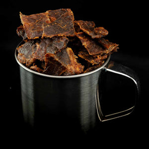 Stålkopp fylt med Kuivalihakundi Greasy Pork Jerky Røkt Eple-BBQ på sort bakgrunn