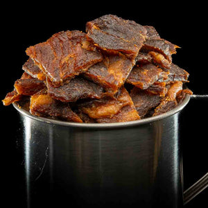 Stålkopp fylt med Kuivalihakundi Greasy Pork Jerky Koreansk Stil på sort bakgrunn