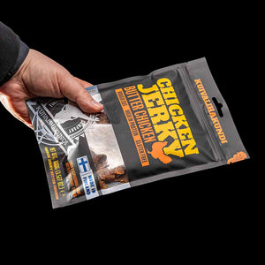 Hånd som holder en pose Kuivalihakundi Kylling Jerky Butter Chicken
