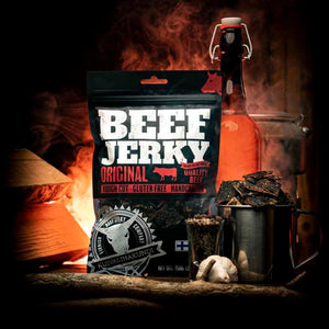 Kuivalihakundi Beef Jerky Original i et mørkt rom med flaske, flammer og stålkopp med biter