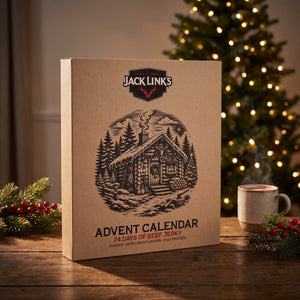 Jack Link's julekalender på et trebord med tent juletre, granbar og en kopp i bakgrunnen