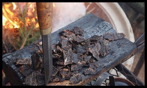 Kniv og grovkuttet Kuivalihakundi Hot Naga beef jerky på en fjøl ved bålet