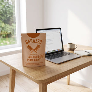 Barazzo Tørket Svinefilet Honning & Sennep på skrivebordet ved siden av laptop, kaffekopp og notatbok, AI-generert bilde