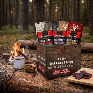 Beef & Beyond Box - Jack Link's & Renjer Mix på en stokk ved bålet i furuskogen i skumringen, med emaljekopp og kuksa, AI-generert bilde