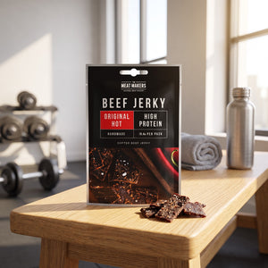 Meat Makers Beef Jerky Hot på en benk på treningssenteret, med manualer, håndkle og drikkeflaske i bakgrunnen, AI-generert bilde
