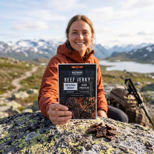 Turgåer tar en pause på fjellet og holder Meat Makers Beef Jerky Smoky, AI-generert bilde