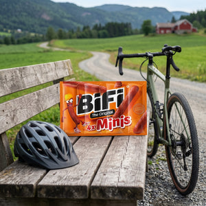 BiFi Minis 4-pack på en benk ved grusveien, med sykkel og sykkelhjelm, AI-generert bilde