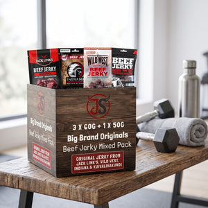 Big Brand Originals Beef Jerky Mixed Pack på en benk på treningssenteret, med manualer, håndkle og drikkeflaske i bakgrunnen, AI-generert bilde
