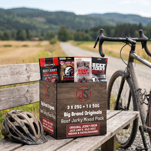 Big Brand Originals Beef Jerky Mixed Pack på en benk ved grusveien, med sykkel og sykkelhjelm, AI-generert bilde