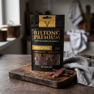 Biltong Premium Original på en mørk skjærefjøl på kjøkkenbenken i dempet vinduslys, AI-generert bilde
