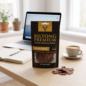 Biltong Premium Original på skrivebordet ved siden av laptop, kaffekopp og notatbok, AI-generert bilde