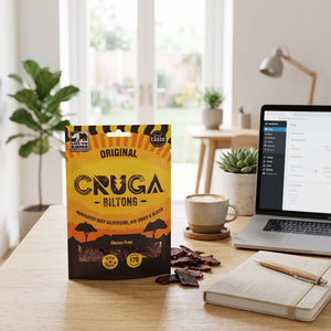 Cruga Biltong Original på skrivebordet ved siden av laptop, kaffekopp og notatbok, AI-generert bilde