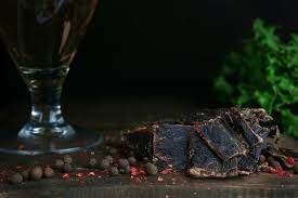 Nærbilde av Kuivalihakundi beef jerky med pepperkorn og et glass i bakgrunnen