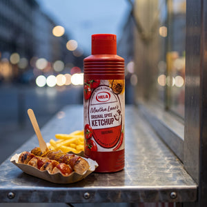 Hela Curry Ketchup Original på disken i en gatekjøkkenbod ved en papirskål med oppskåret pølse, currysaus og pommes frites, AI-generert bilde