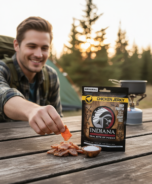 Smilende mann tar en bit Indiana Kylling Jerky Original ved teltet på campingplassen, AI-generert bilde