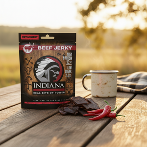 Indiana Beef Jerky Hot & Sweet på et trebord ute med emaljekopp, jerkybiter og rød chili, AI-generert bilde