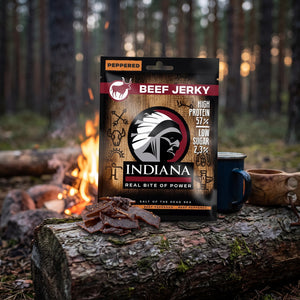 Indiana Beef Jerky Peppered på en stokk ved bålet i furuskogen i skumringen, med emaljekopp og kuksa, AI-generert bilde