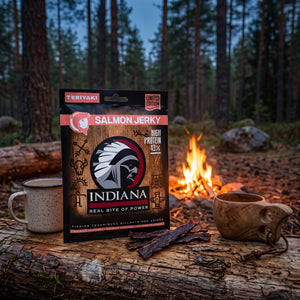 Indiana Laks Jerky Teriyaki på en stokk ved bålet i furuskogen i skumringen, med emaljekopp og kuksa, AI-generert bilde