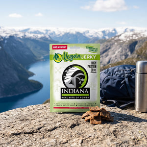 Indiana Vegansk Jerky Hot & Sweet på en stein ved en fjellsti høyt over fjorden, med ryggsekk og termos, AI-generert bilde