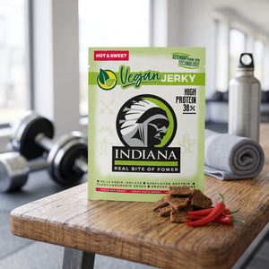 Indiana Vegansk Jerky Hot & Sweet på en benk på treningssenteret, med manualer, håndkle og drikkeflaske i bakgrunnen, AI-generert bilde