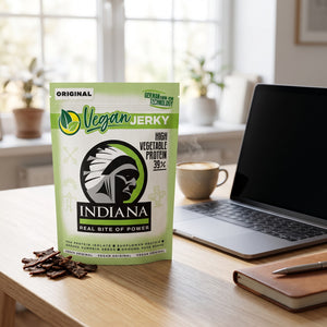 Indiana Vegansk Jerky Original på skrivebordet ved siden av laptop, kaffekopp og notatbok, AI-generert bilde