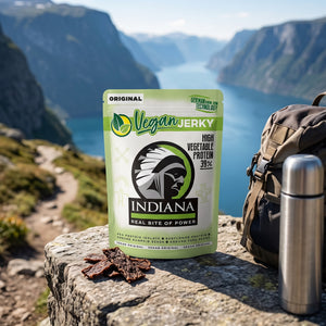 Indiana Vegansk Jerky Original på en stein ved en fjellsti høyt over fjorden, med ryggsekk og termos, AI-generert bilde