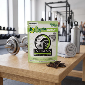 Indiana Vegansk Jerky Original på en benk på treningssenteret, med manualer, håndkle og drikkeflaske i bakgrunnen, AI-generert bilde