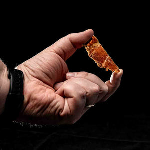 En bit Kuivalihakundi kyllingjerky holdt mellom to fingre