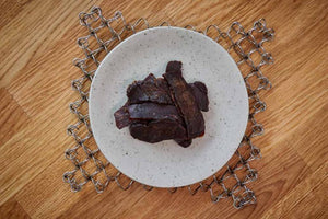 KJØ Goddamn Spicy beef jerky på en tallerken på et trebord, sett ovenfra