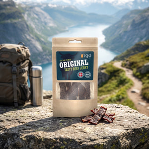 KJØ Tasty Beef Jerky på en stein ved en fjellsti høyt over fjorden, med ryggsekk og termos, AI-generert bilde