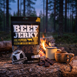 Kuivalihakundi Beef Jerky Fem Pepper på en stokk ved bålet i furuskogen i skumringen, med emaljekopp og kuksa, AI-generert bilde