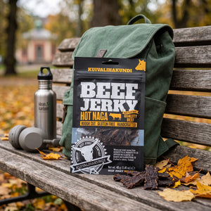 Kuivalihakundi Beef Jerky Hot Naga stikker opp av en ryggsekk på en parkbenk om høsten, med drikkeflaske og hodetelefoner, AI-generert bilde