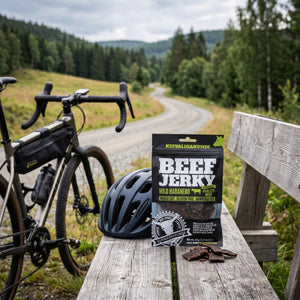 Kuivalihakundi Beef Jerky Mild Habanero på en benk ved grusveien, med sykkel og sykkelhjelm, AI-generert bilde