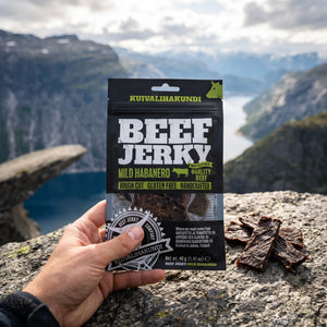 Hånd som holder Kuivalihakundi Beef Jerky Mild Habanero foran et fjordlandskap, AI-generert bilde