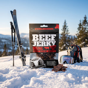 Kuivalihakundi Beef Jerky Original i snøen ved siden av turski og staver på en solrik vinterdag i fjellet, AI-generert bilde