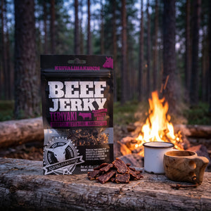 Kuivalihakundi Beef Jerky Teriyaki på en stokk ved bålet i furuskogen i skumringen, med emaljekopp og kuksa, AI-generert bilde