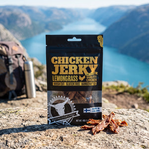 Kuivalihakundi Kylling Jerky med Sitrongress på en stein ved en fjellsti høyt over fjorden, med ryggsekk og termos, AI-generert bilde