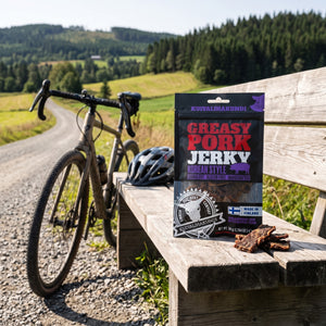 Kuivalihakundi Greasy Pork Jerky Koreansk Stil på en benk ved grusveien, med sykkel og sykkelhjelm, AI-generert bilde