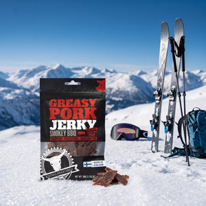 Kuivalihakundi Greasy Pork Jerky Røkt BBQ i snøen ved siden av turski og staver på en solrik vinterdag i fjellet, AI-generert bilde