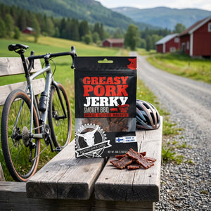 Kuivalihakundi Pork Jerky Røkt BBQ på en benk ved grusveien, med sykkel og sykkelhjelm, AI-generert bilde