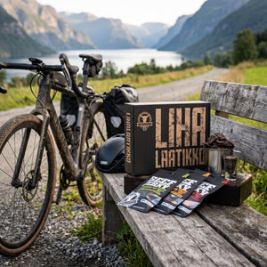 Kuivalihakundi The Meat Box 8 poser jerky på en benk ved grusveien, med sykkel og sykkelhjelm, AI-generert bilde