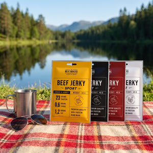 Meat Makers Sports Beef Jerky Pakkepris på et rutete piknikteppe ved et skogsvann en sommerdag, med stålkopp og solbriller, AI-generert bilde
