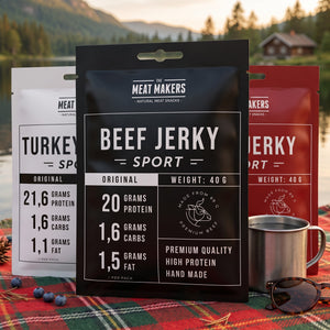 Meat Makers Sports Beef Jerky Pakkepris på et rutete piknikteppe ved et skogsvann en sommerdag, med stålkopp og solbriller, AI-generert bilde