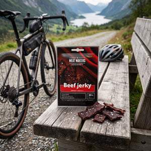 Meat Makers Beef Sweet Chilli Gourmet på en benk ved grusveien, med sykkel og sykkelhjelm, AI-generert bilde