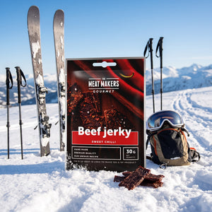 Meat Makers Beef Sweet Chilli Gourmet i snøen ved siden av turski og staver på en solrik vinterdag i fjellet, AI-generert bilde