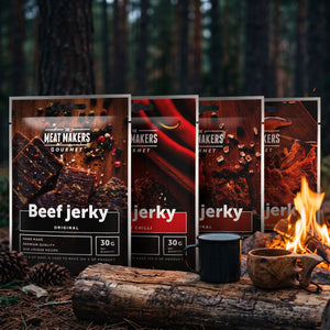 Meat Makers Gourmet Pakkepris på en stokk ved bålet i furuskogen i skumringen, med emaljekopp og kuksa, AI-generert bilde