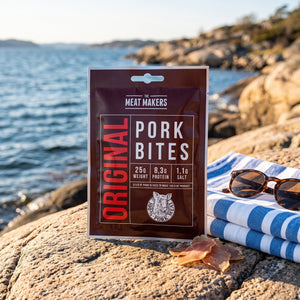 Meat Makers Lufttørket biter av Svineindrefilet på et svaberg ved sjøen, med håndkle og solbriller, AI-generert bilde