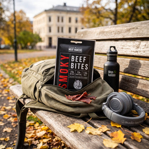 Meat Makers Røkt og tørket Oksefiletbiter stikker opp av en ryggsekk på en parkbenk om høsten, med drikkeflaske og hodetelefoner, AI-generert bilde