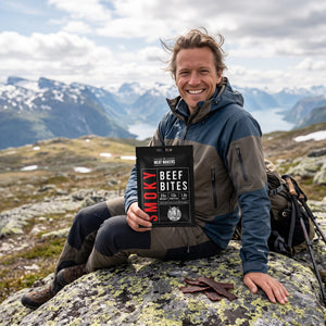Turgåer tar en pause på fjellet og holder Meat Makers Røkt og tørket Oksefiletbiter, AI-generert bilde